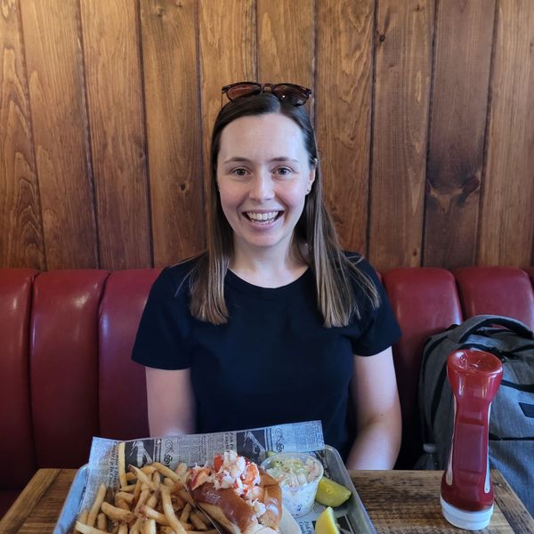 Alaina smiling in a diner booth with a lobster roll and fries