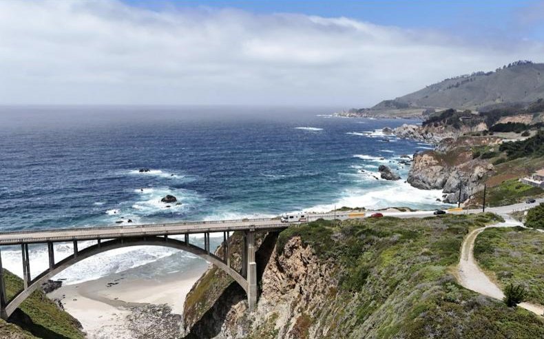 A coastal highway bridge spanning a rocky cove above the ocean