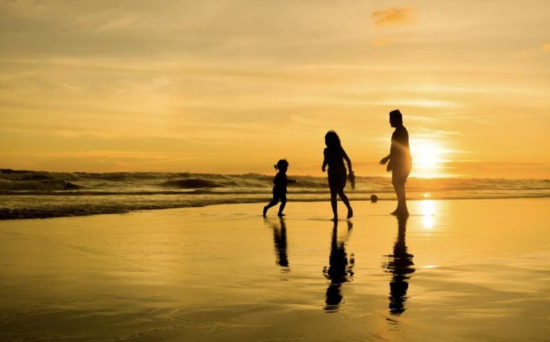 A family silhouetted on a beach at sunset